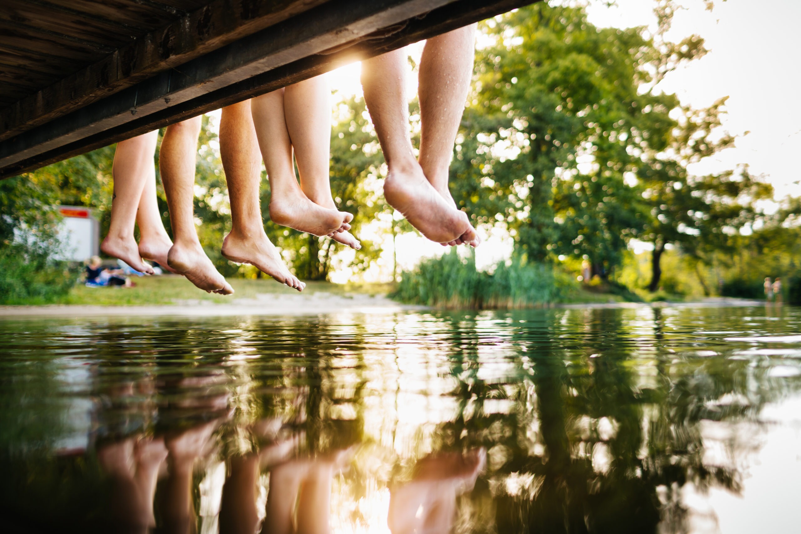 vier junge Menschen sitzen auf einem Bootssteg